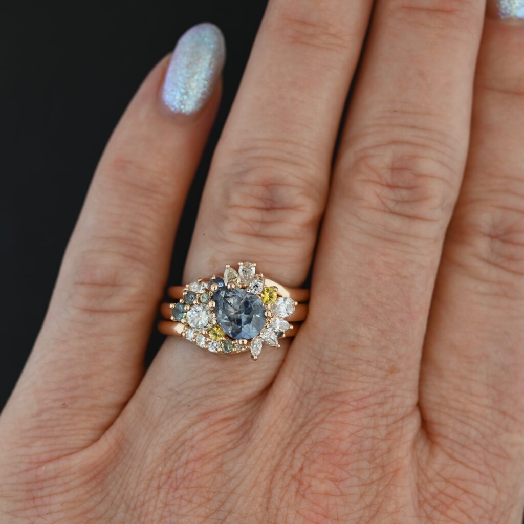https://b2069773.smushcdn.com/2069773/wp-content/uploads/2023/10/custom-wedding-rings-rose-gold-pear-cut-diamond-montana-sapphire-Elana-bands-set-on-hand-1024x1024.jpg?lossy=1&strip=1&webp=1